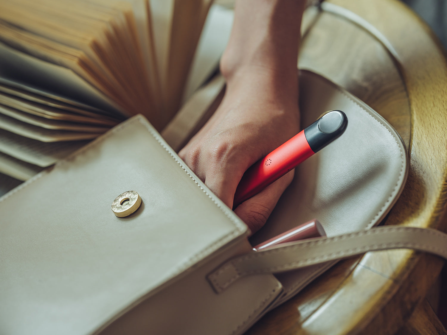 A woman taking her RELX Infinity device out of her beige purse.