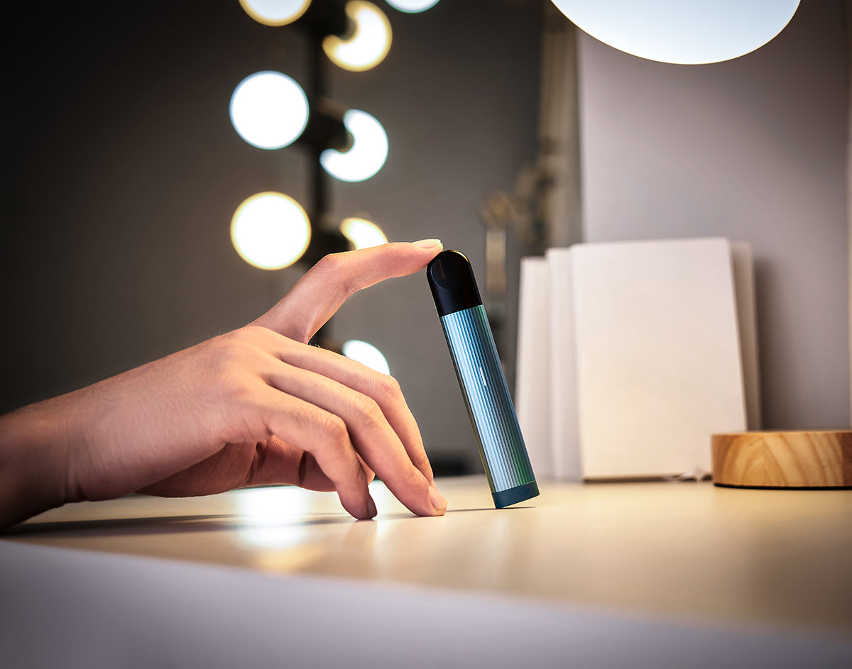 A person holding a RELX vape device vertically using their index finger.