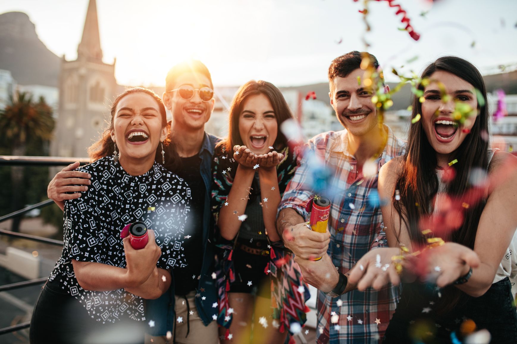 Group of friends enjoying party and throwing confetti
