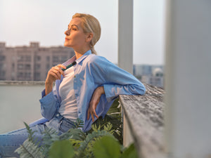Woman relaxing on the rooftop while holding RELX Infinity device and gazing at the distance