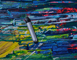 A silver RELX vape lies on a multicolored surface.