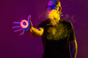 A man reaches out to a smoke ring from a vape.