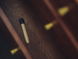 A gold RELX vape inside a wooden drawer