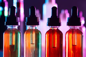 Four bottles of vape e-juice are lit by a bright background.
