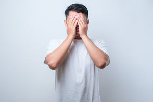 A man covers his face in exasperation.